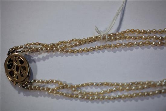 A late 19th/early 20th century triple strand graduated natural pearl necklace with gold, ruby and diamond set oval clasp, 22in.